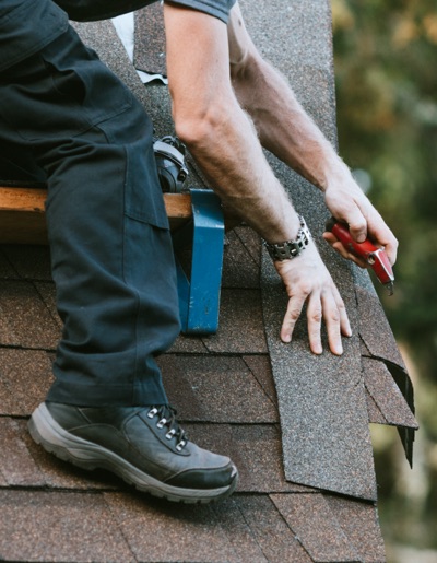 Image of Professional Roofer cutting asphalt shingles for Urban Exteriors